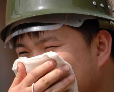 A firefighter covers his face with a tower at a site of a gas leakage in Kaixian County, Southwest China's Sichuan Province March 28, 2006. [Xinhua]