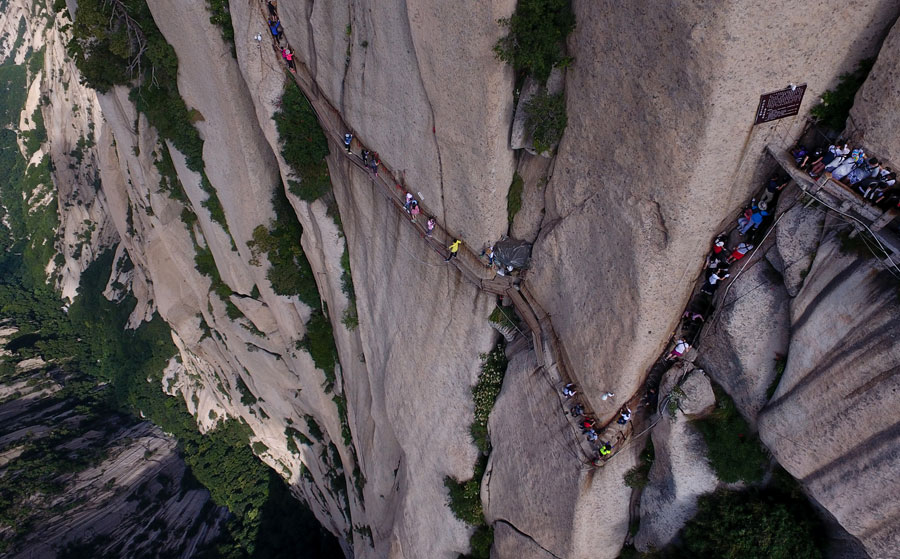 Tourists walk on plank road built on cliff at Huashan Mountain