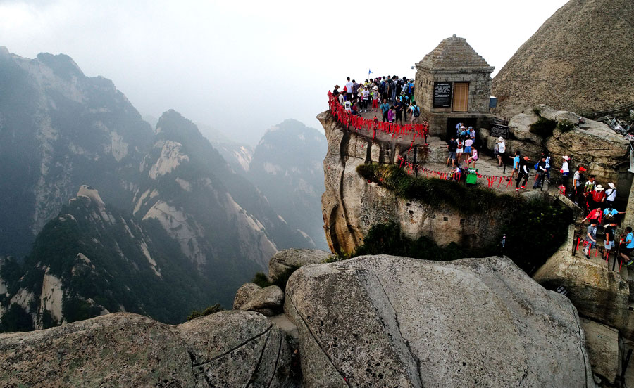 Tourists walk on plank road built on cliff at Huashan Mountain