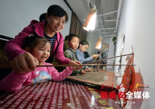 Youngsters play with puppets in Tai'an